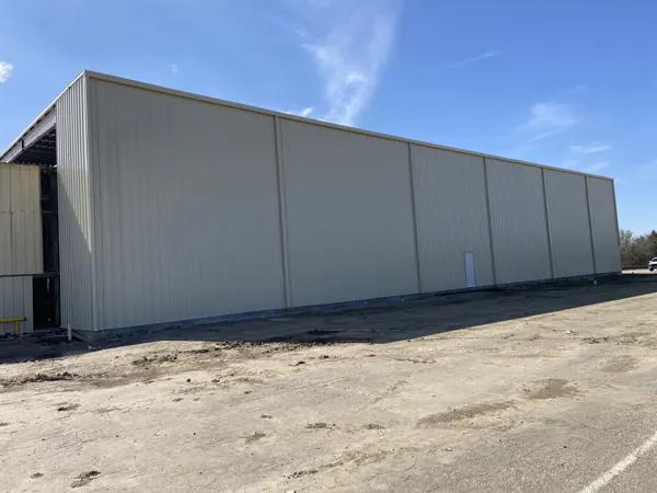 Bolt-up metal building with a wide side elevation on a graded pad, Denison, TX