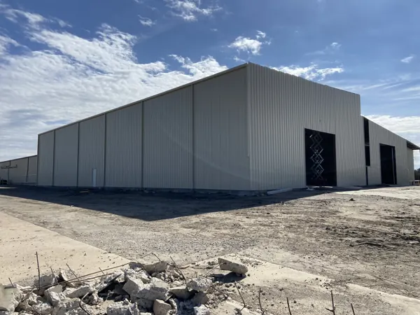 Grey bolt-up metal building shell with the slab poured, Pottsboro, TX