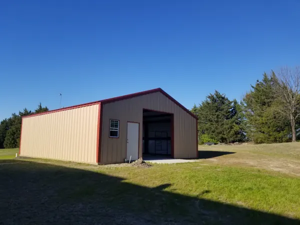 Pre-engineered steel building in tan with red trim, Calera, OK