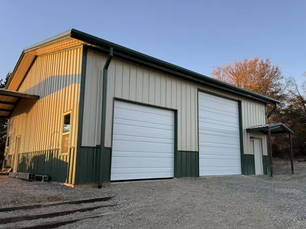 Tan metal building with green trim and two overhead doors, Pottsboro, TX