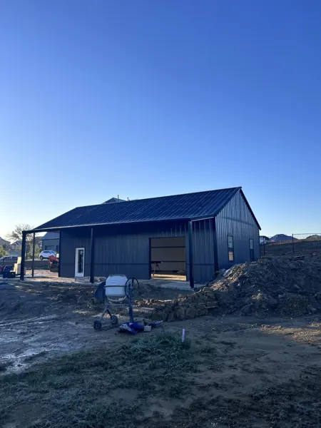 Navy blue metal building with white trim during construction, Howe, TX