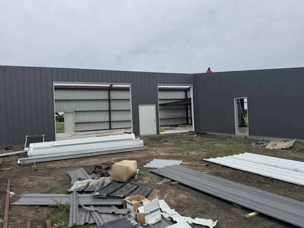 Grey wall panels on a metal building with panel bundles on site, Howe, TX