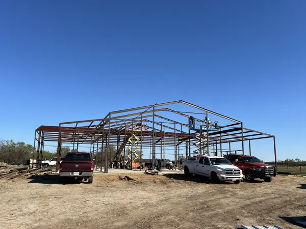 Steel frame with trucks on site during erection, Van Alstyne, TX