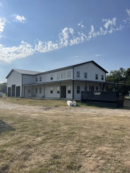 Two-storey grey barndominium with a workshop bay, Sherman, TX
