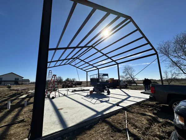 Steel frame silhouetted at dusk with a lift on the slab, Sherman, TX