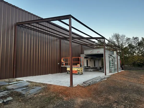 Steel frame and lean-to going up on a brown metal building, Denison, TX