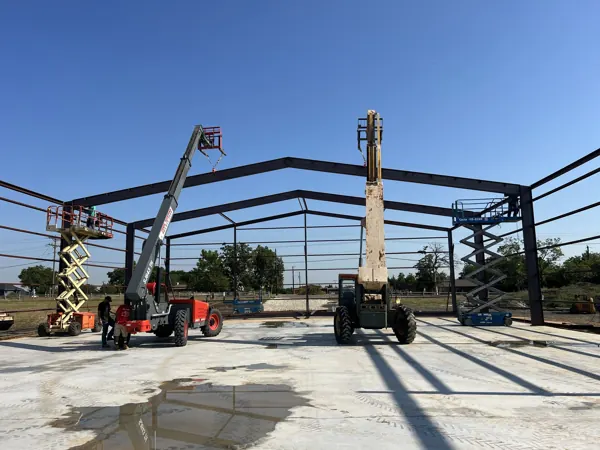Steel frame with two telehandlers setting beams, Howe, TX