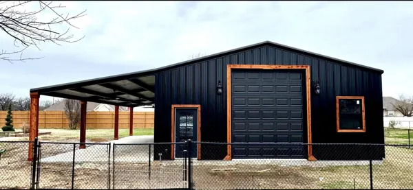 Black barndominium with cedar posts and a black garage door, Denison, TX