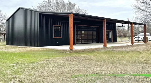 Black barndominium with a cedar-framed porch, Denison, TX