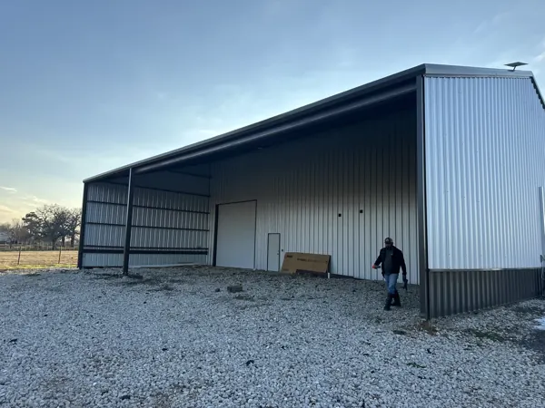 Metal building with an open bay and a worker walking through, Sherman, TX
