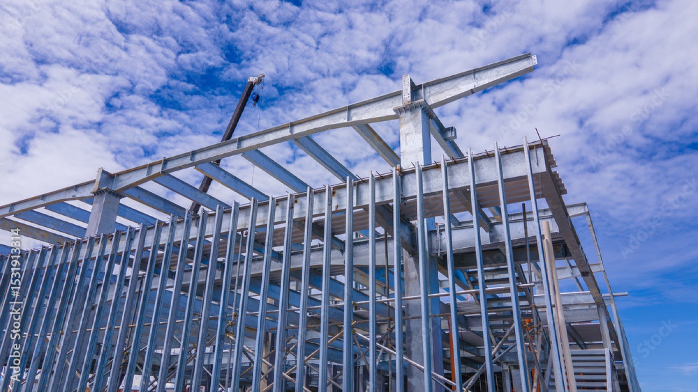 Steel building frame erected by Metal Warehouse Inc. against a blue sky